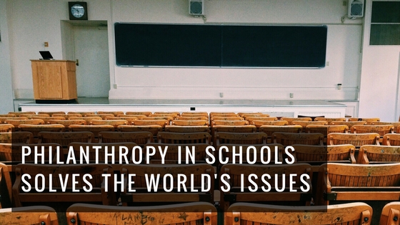 View of an empty classroom with wooden desks facing the front of the room with a large board, image used for Ari Monkarsh blog about how philanthropy in schools helps the world