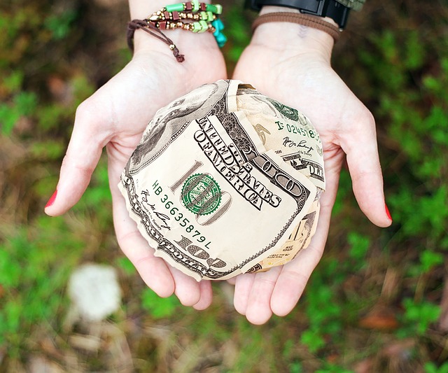 Cupped hands holding a ball of money, offering it in charity, image used for Ari Monkarsh blog about corporate philanthropy